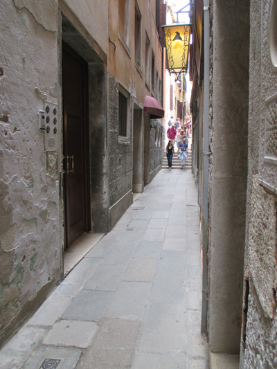 Photo shows a narrow alley with a stairway at the end with about 7 steps going up.